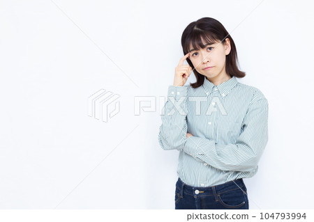 A woman in her thirties who is seriously worried in front of a white background A woman in her thirties who is seriously worried in front of a white background 104793994