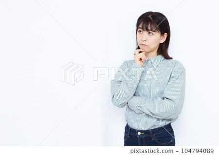 A woman in her thirties who is seriously worried in front of a white background 104794089