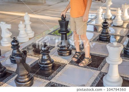 Father and son playing chess spending time together outdoor. Kid play chess Father and son playing chess spending time together outdoor. Kid play chess 104794360