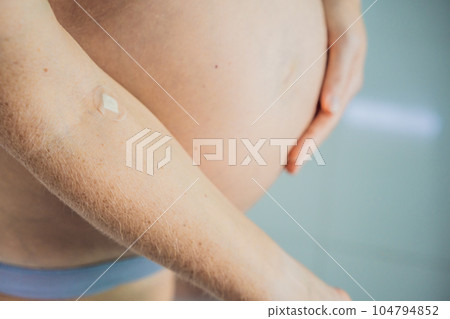 Adhesive bandage on arm after blood test from pregnant woman in gynecological clinic. Prenatal testing. Medical Equipment, Adhesive bandage on a female brachium in medical clinic. Close up, Top view Adhesive bandage on arm after blood test from pregnant woman in gynecological clinic. Prenatal testing. Medical Equipment, Adhesive bandage on a female brachium in medical clinic. Close up, Top view 104794852