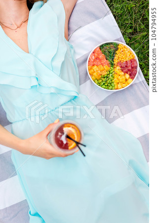 Woman on a blanket with a drink and poke bowl Woman on a blanket with a drink and poke bowl 104794955