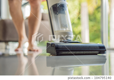 Modern vacuum cordless vacuum cleaner with water nozzle for cleaning floors. Close-up of a washing vacuum cleaner on the floor House cleaning Modern vacuum cordless vacuum cleaner with water nozzle for cleaning floors. Close-up of a washing vacuum cleaner on the floor House cleaning 104795140