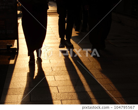 日落時男人和女人在人行道上行走的剪影 104795567