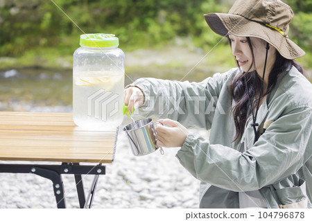 年輕女子從飲料服務器倒檸檬水戶外圖像 104796878