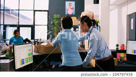 Diverse workers preparing online orders, putting trendy clothes in cardboard boxes in clothing store. Boutique employees working at packages delivery, shipping to customers in shopping mall Diverse workers preparing online orders, putting trendy clothes in cardboard boxes in clothing store. Boutique employees working at packages delivery, shipping to customers in shopping mall 104797456