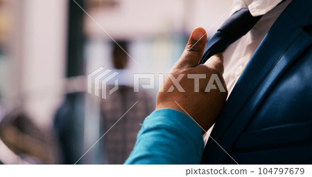 African american customer checking elegant tie fabric, wanting to buy formal suit for husband in modern boutique. Client shopping for new wardrobe, buying trendy merchandise in clothing store 104797679