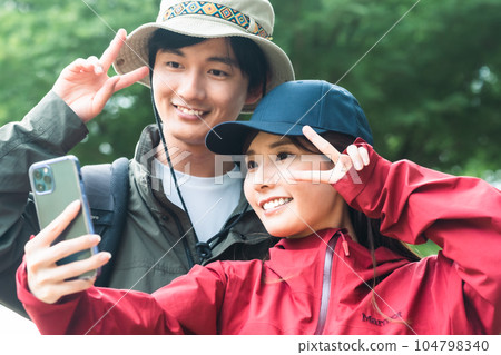 Young couple taking smartphone photos while trekking 104798340