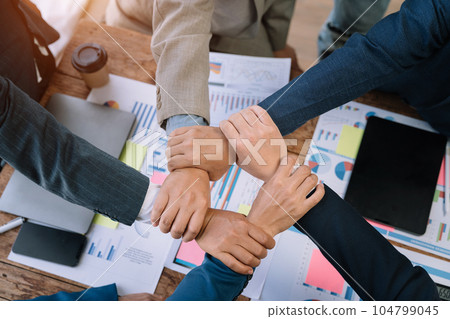 Close up business people holding each others wrists, join hands together, support and unity, team strength and power, colleagues involved in team building activity. 104799045