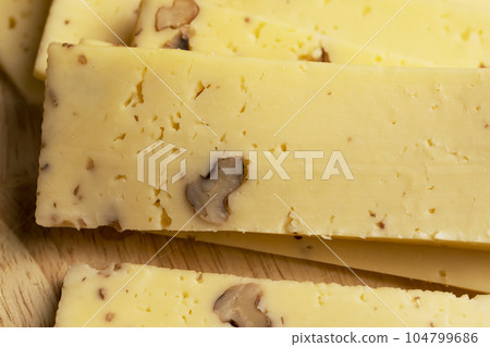 Sliced piece of milk cheese with walnuts 104799686