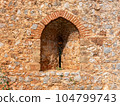 An ancient stone wall of Alanya fortress with an arched window 104799743