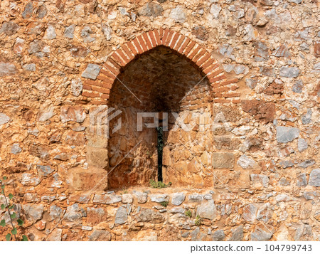 An ancient stone wall of Alanya fortress with an arched window An ancient stone wall of Alanya fortress with an arched window 104799743
