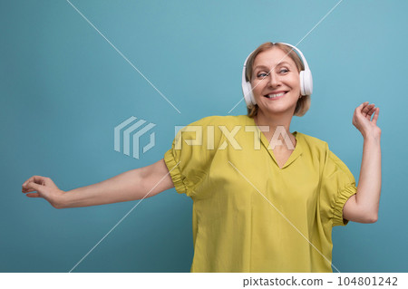 portrait of a blond adult woman dancing to her playlist listening to music in headphones portrait of a blond adult woman dancing to her playlist listening to music in headphones 104801242