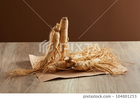 Minimalist style, advertising photo for product. Ginseng roots on wooden background. Traditional Chinese medicine has used ginseng for thousands of years to improve overall health. 104801253