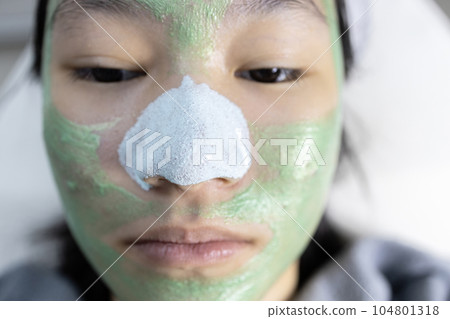 Asian young woman doing facial treatment,removing acne pimples on nose,blackhead removal with nose peeling mask,teen girl applying cream mask with natural herbs homemade facial masks,skin care concept Asian young woman doing facial treatment,removing acne pimples on nose,blackhead removal with nose peeling mask,teen girl applying cream mask with natural herbs homemade facial masks,skin care concept 104801318