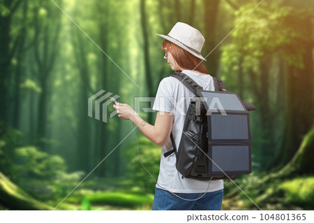 Female hiker with smartphone in hands carrying backpack with charging solar panel onforest background 104801365