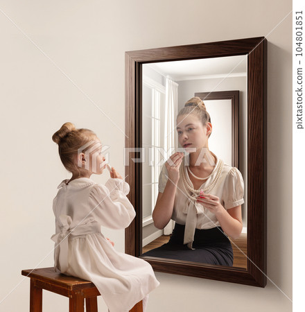 Creative conceptual collage. Little girl looking in mirror and seeing reflection of young girl, her future self. Aging Creative conceptual collage. Little girl looking in mirror and seeing reflection of young girl, her future self. Aging 104801851