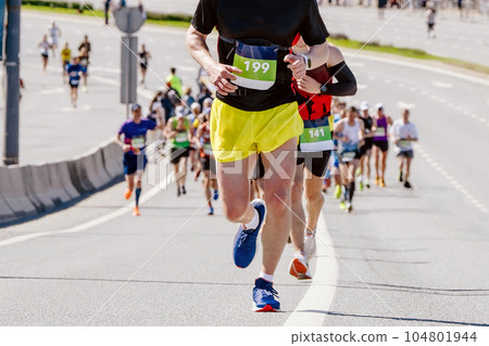 leading athlete runner running at head of large group runners marathon race, summer sports event 104801944