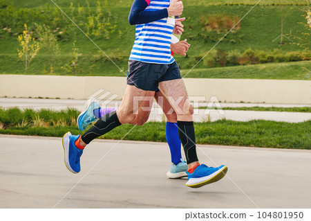 two male athletes runners running together marathon race in landscape park, summer sports event two male athletes runners running together marathon race in landscape park, summer sports event 104801950