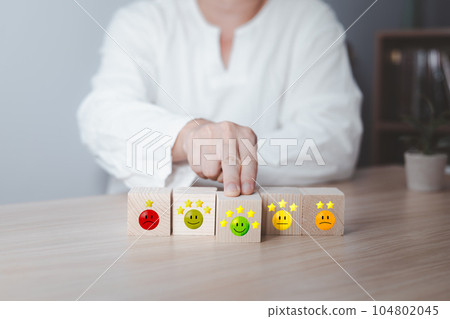 Hand of a businessman chooses a smile face on wood block circle.Customer service experience and business satisfaction survey.rating very impressed.Satisfaction survey concept.five Star Satisfaction 104802045