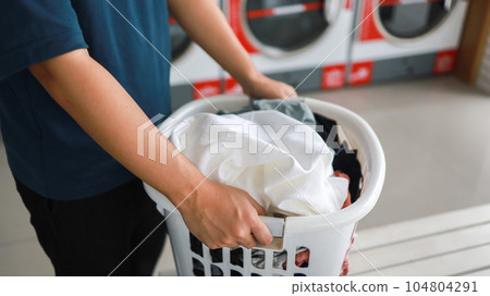House husband with Basket and dirty laundry washed clothing in laundry room interior. washing machine at laundry business store House husband with Basket and dirty laundry washed clothing in laundry room interior. washing machine at laundry business store 104804291