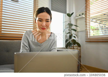 Happy young woman using laptop at home, chatting with friends in social network, watching movie and shopping online Happy young woman using laptop at home, chatting with friends in social network, watching movie and shopping online 104805036