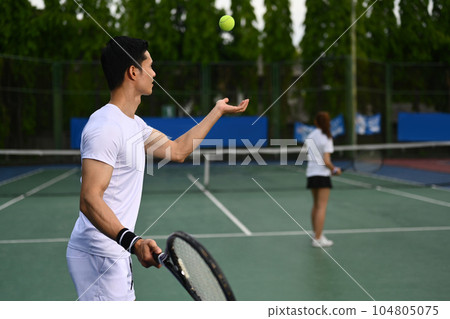 Shot of male tennis player with racket serving ball during match. Outdoor sports and healthy lifestyle concept 104805075