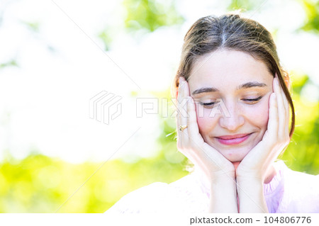 the beautiful girl in a beautiful dress outdoors, touches by hands of the person and smiles blindly 104806776