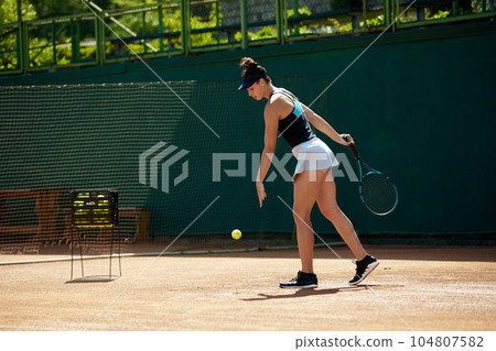 Young girl, athlete in sportswear training outside. Female tennis player during game at open air sport court Young girl, athlete in sportswear training outside. Female tennis player during game at open air sport court 104807582
