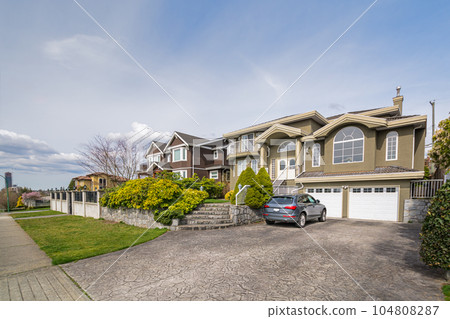 Luxury residential houses with a car in front on cloudy day in Vancouver, Canada Luxury residential houses with a car in front on cloudy day in Vancouver, Canada 104808287