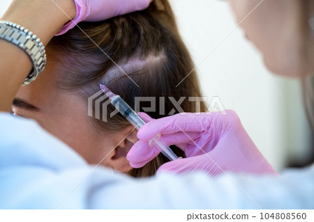 Hair loss treatment, unrecognizable woman head and doctor's hands with syringe. 104808560