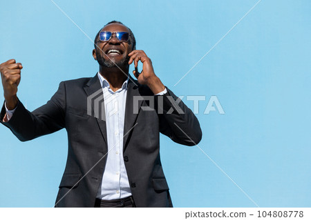 African american businessman talking on the phone and looking excited African american businessman talking on the phone and looking excited 104808778