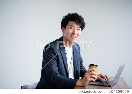 A man using a computer with a cup of coffee A man using a computer with a cup of coffee 104809059
