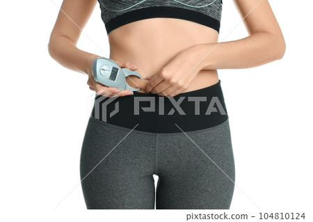 Young woman measuring body fat with caliper on white background, closeup Young woman measuring body fat with caliper on white background, closeup 104810124