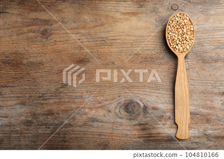 Spoon with green buckwheat on wooden table, top view. Space for text 104810166