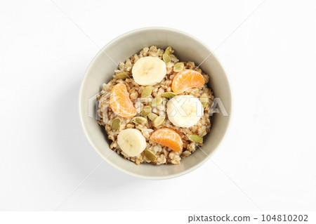 Tasty oatmeal with fruits and pumpkin seeds isolated on white, top view. Healthy breakfast 104810202