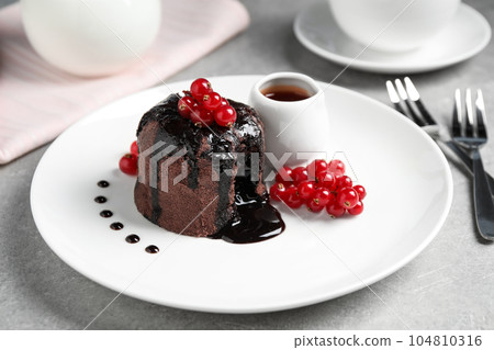 Delicious warm chocolate lava cake with berries on grey table 104810316