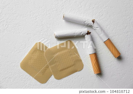Nicotine patches and broken cigarettes on white background, flat lay Nicotine patches and broken cigarettes on white background, flat lay 104810712