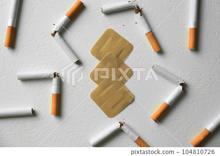 Nicotine patches and broken cigarettes on white background, flat lay Nicotine patches and broken cigarettes on white background, flat lay 104810726