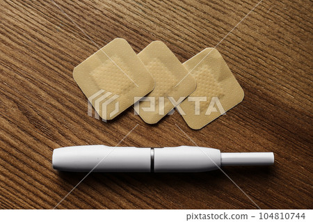 Nicotine patches and electronic cigarette on wooden table, flat lay Nicotine patches and electronic cigarette on wooden table, flat lay 104810744