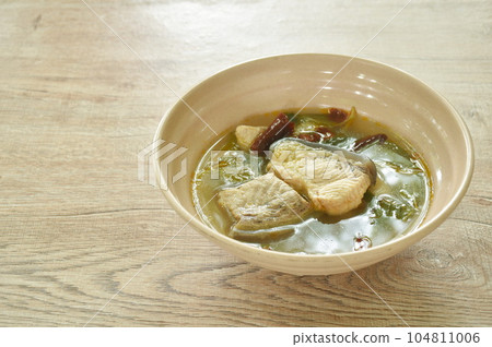 spicy boiled Maekong giant catfish with herb and chili tom yum soup on bowl 104811006