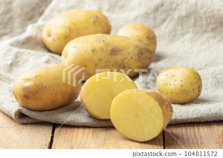 Ripe potato tuber cut in half on coarse burlap fabric. 104811572