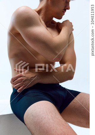 Cropped image of young man with strong, sportive, muscular body posing shirtless in underwear against white studio background Cropped image of young man with strong, sportive, muscular body posing shirtless in underwear against white studio background 104811953
