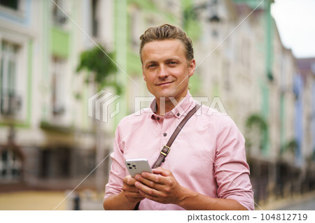 Mid aged man engaged in texting a message while being outdoors. With his mobile phone in hand, he utilizes digital communication to connect with others in the urban environment. High quality photo Mid aged man engaged in texting a message while being outdoors. With his mobile phone in hand, he utilizes digital communication to connect with others in the urban environment. High quality photo 104812719