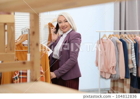 Female business owner talking on phone in boutique 104812836