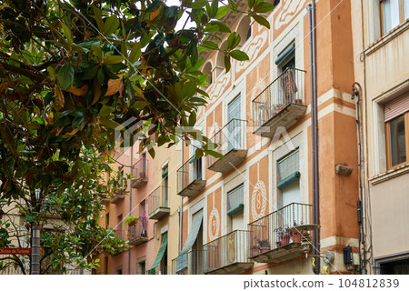 View of old town Girona, Catalonia, Spain, Europe. Summer travel. Eco-friendly building in the city. Green tree branches with leaves and sustainable glass building for reducing heat and carbon dioxide View of old town Girona, Catalonia, Spain, Europe. Summer travel. Eco-friendly building in the city. Green tree branches with leaves and sustainable glass building for reducing heat and carbon dioxide 104812839