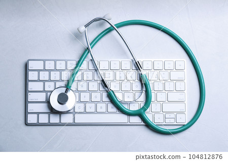 Keyboard and stethoscope on grey stone table, top view. Concept of technical support 104812876