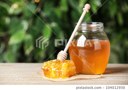 Tasty honey on table against green blurred background Tasty honey on table against green blurred background 104812930