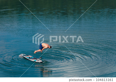 man jump from supboard into the water 104813161