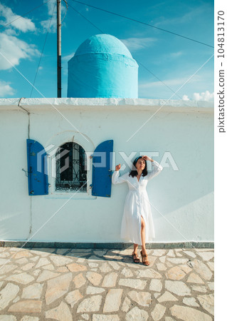 beautiful woman in white dress near old greece church 104813170