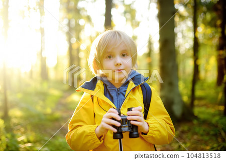 Little boy scout with binoculars during hiking in autumn forest. Child is looking with binoculars. Exploring nature 104813518